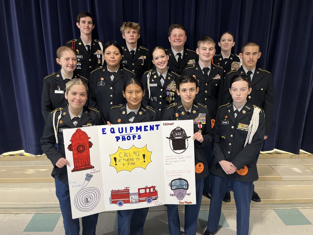 A group of cadets pose for a photo with a fire safety presentation display. 