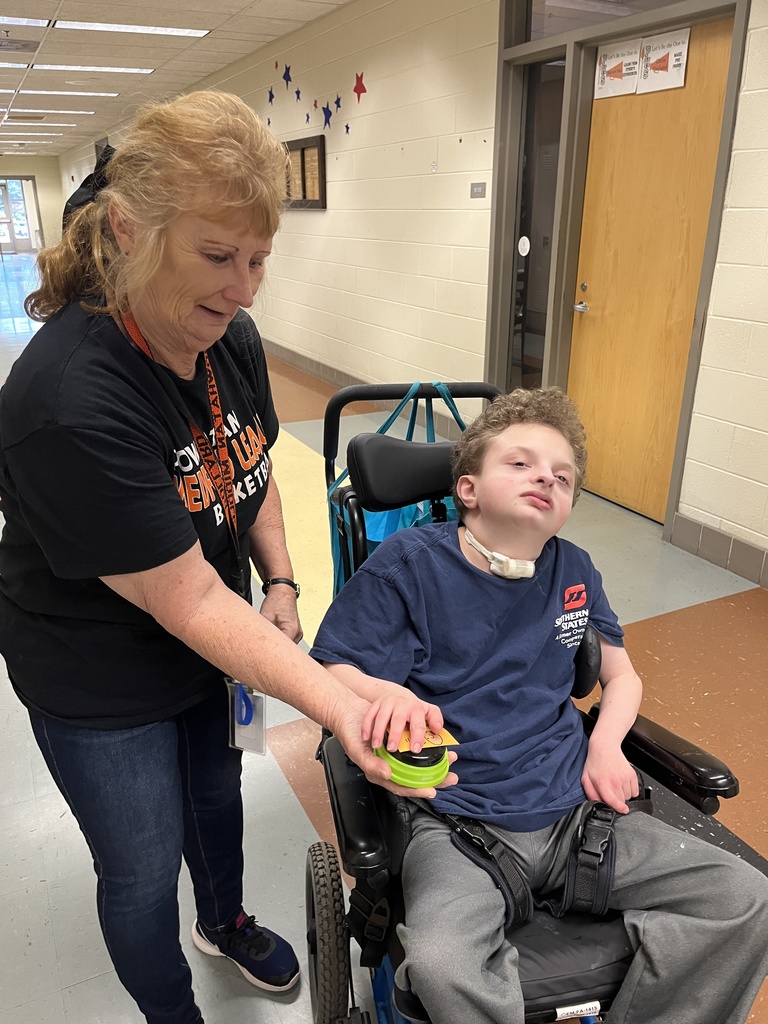 An adult and student pose for a photo along with a coffee cart. 