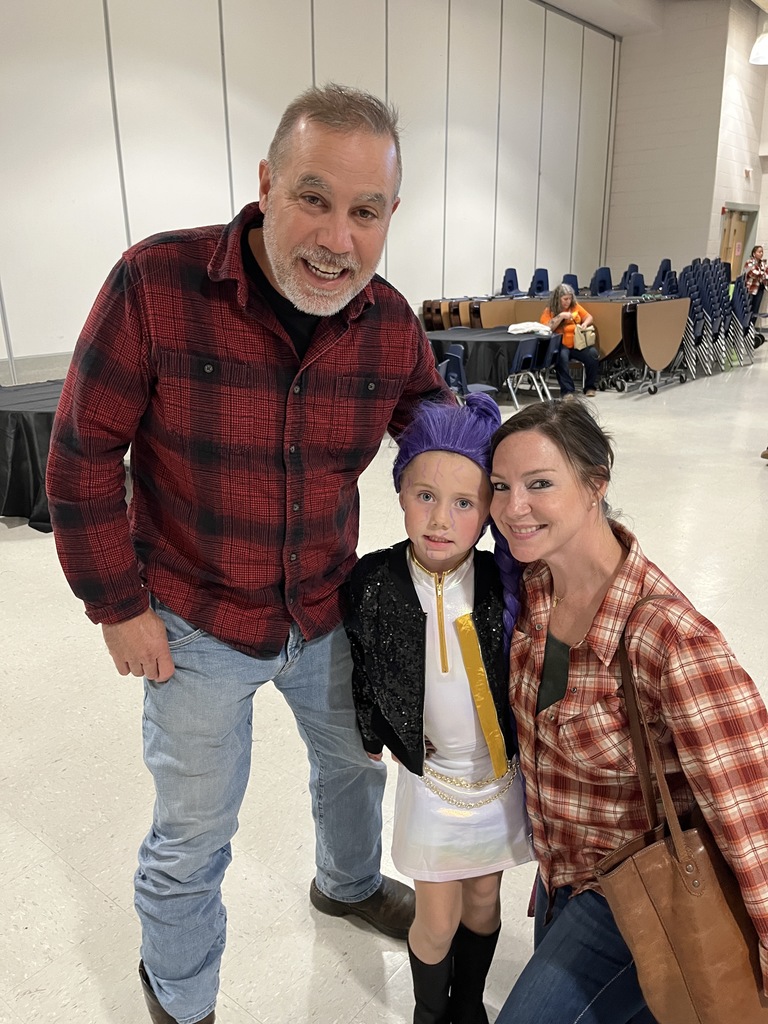 Two adults and a child pose for a photo at a fall festival.