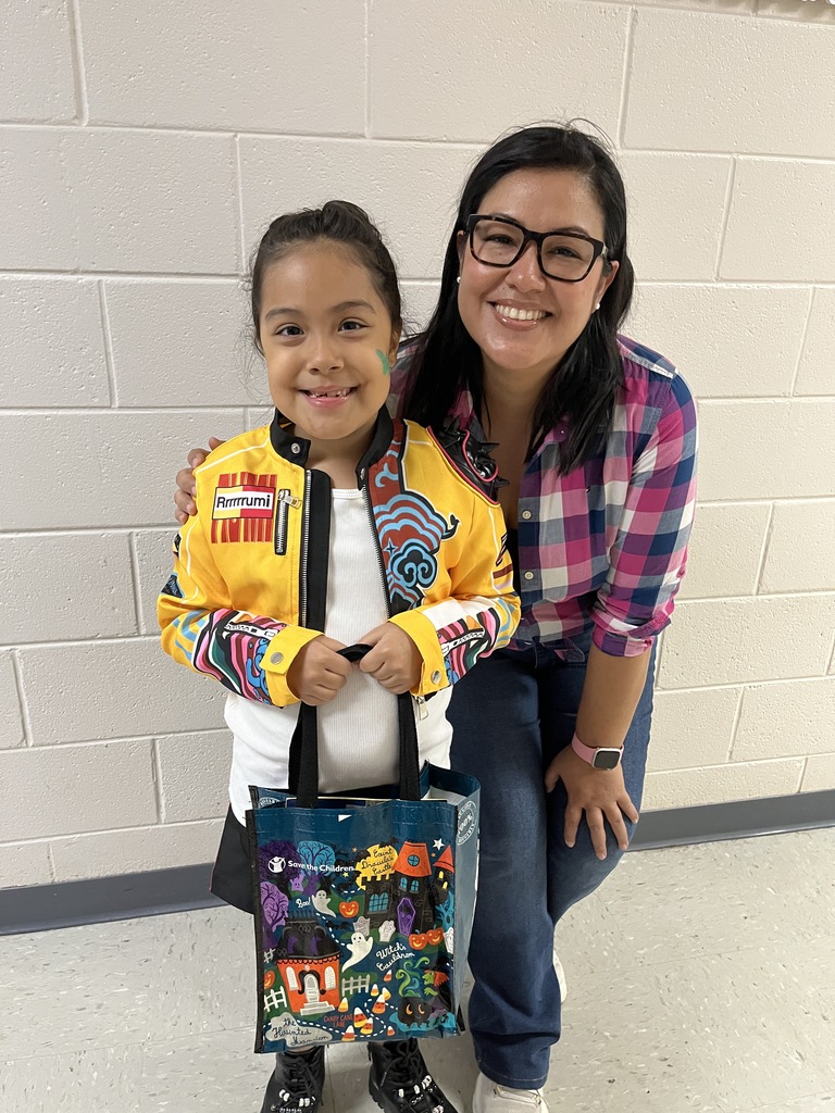 An adult and  child pose for a photo at a fall festival.