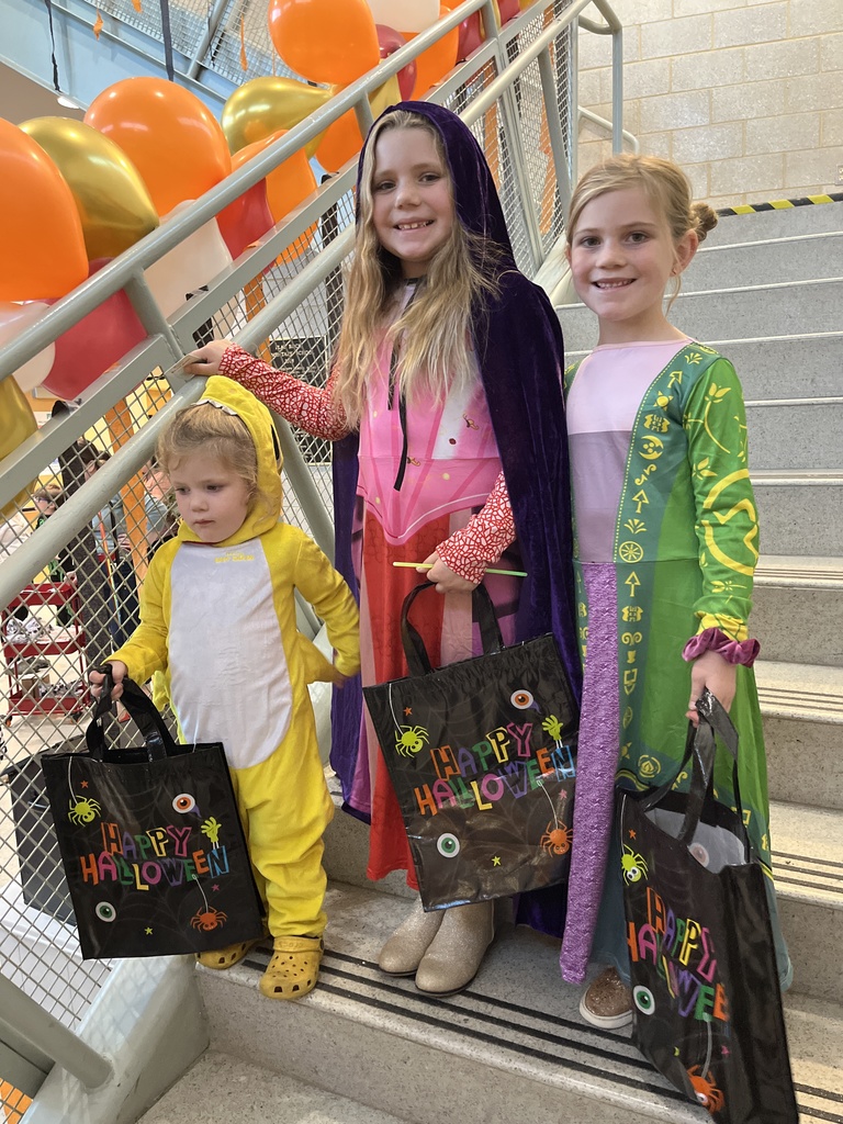 Three children pose for a photo at a fall festival.