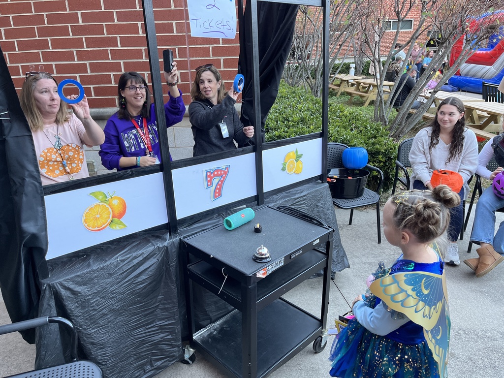 A child plays a game with three adults at a fall festival.