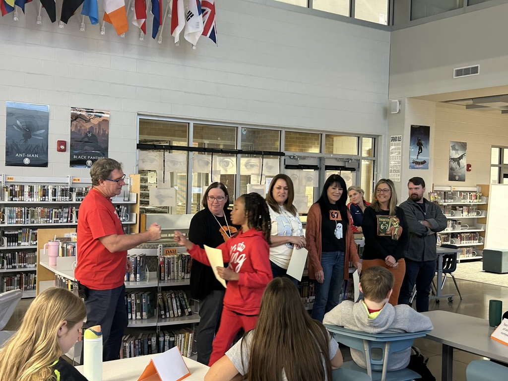 A student accepts a student of the quarter award in an informal ceremony in a library. 