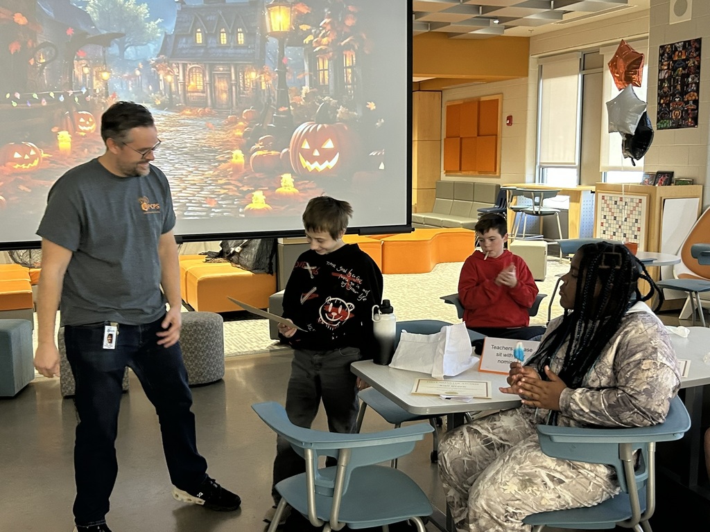 A student accepts a student of the quarter award in an informal ceremony in a library. 