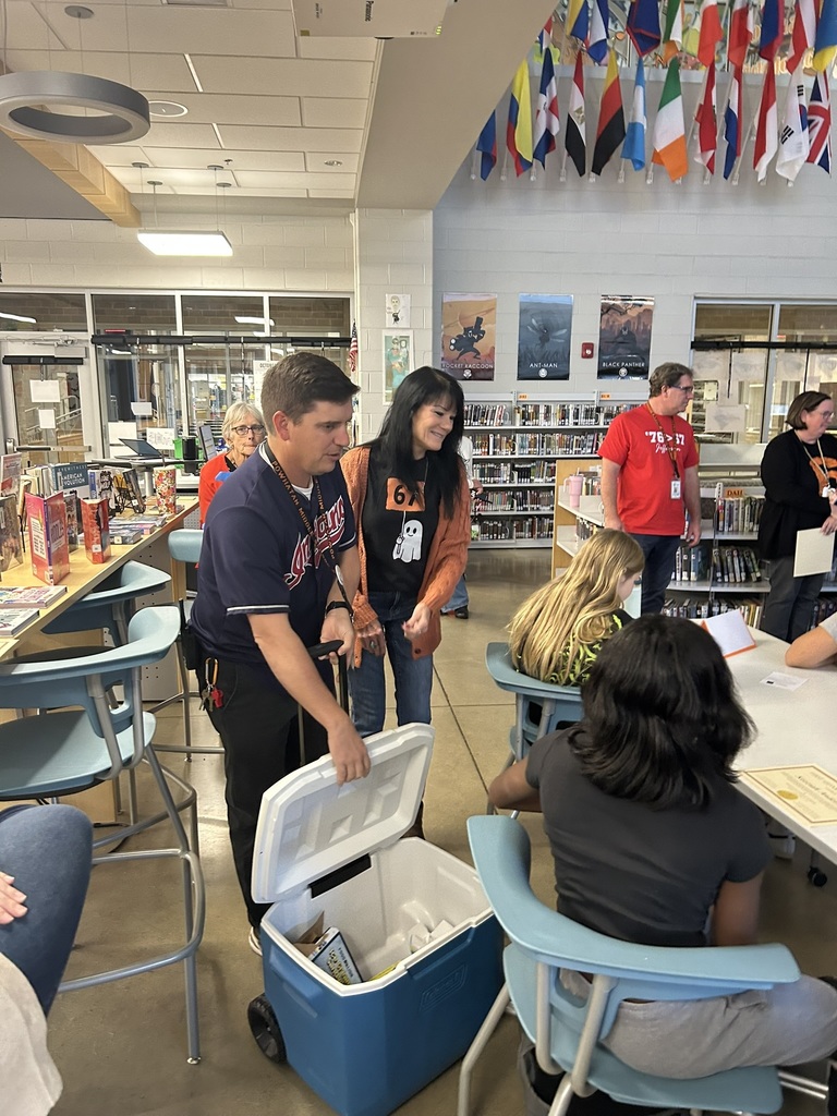 A student accepts a student of the quarter award in an informal ceremony in a library. 