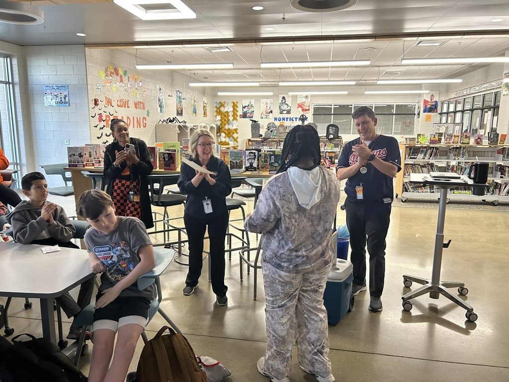 A student accepts a student of the quarter award in an informal ceremony in a library. 