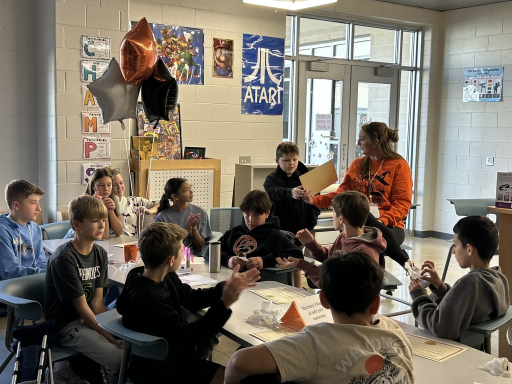 A student accepts a student of the quarter award in an informal ceremony in a library. 
