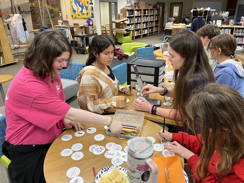Teens make buttons at a high school spookfest. 
