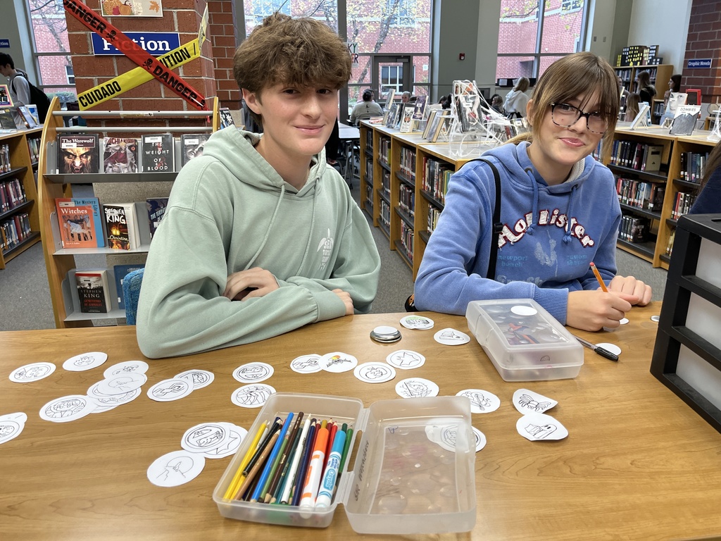 Teens make buttons at a high school spookfest. 