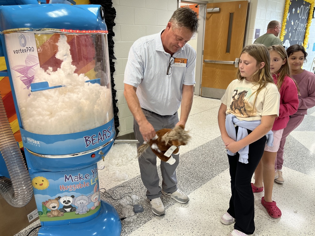 Students watch an adult stuff new stuffed animals.