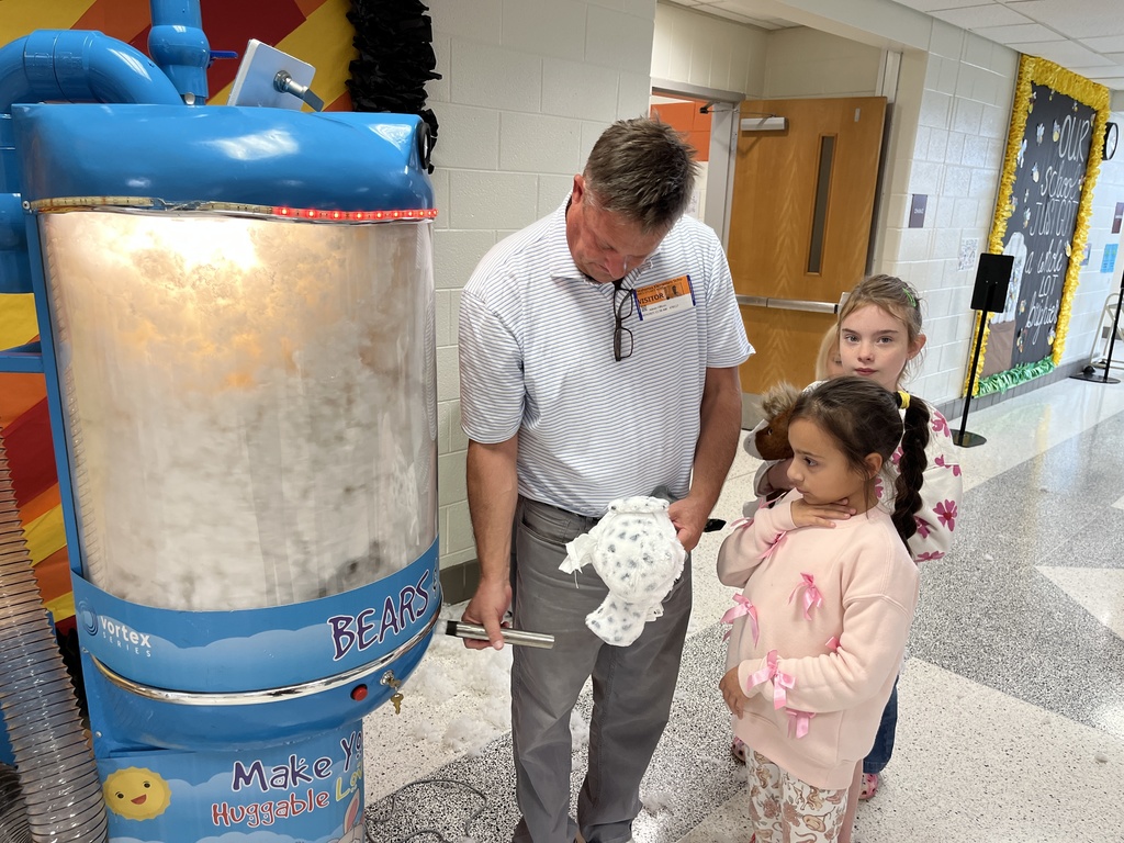 Students watch an adult stuff new stuffed animals.