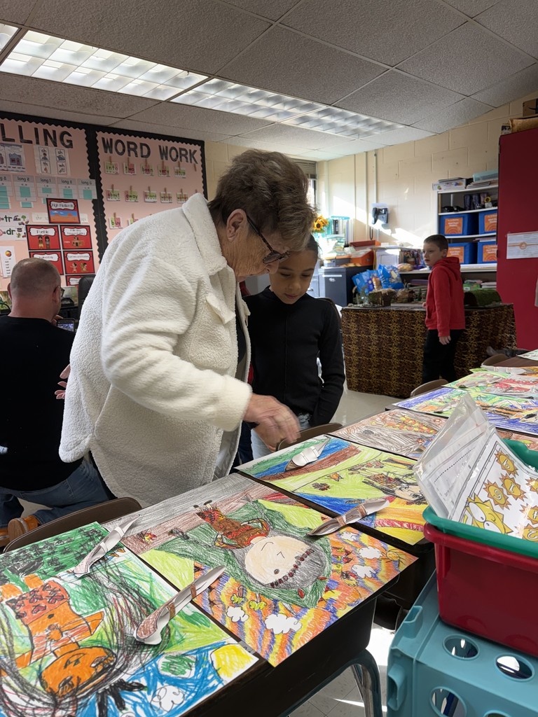 An adult and child observe work on display for a class's Native American Museum.