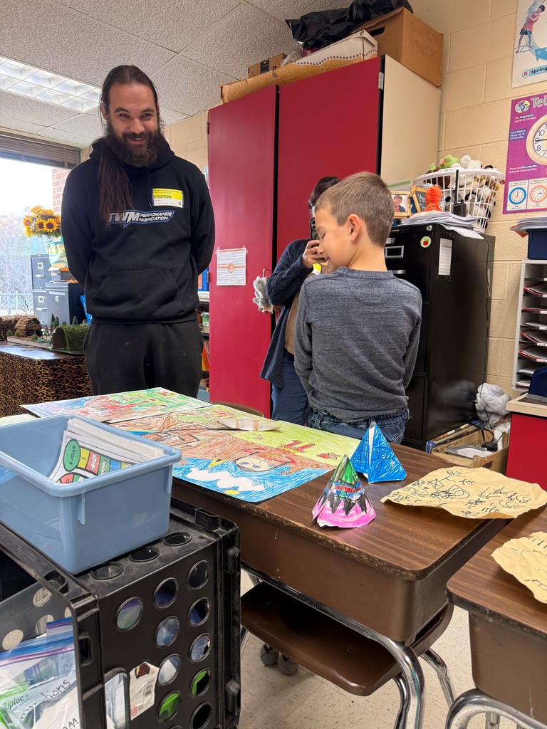 An adult and child observe work on display for a class's Native American Museum.