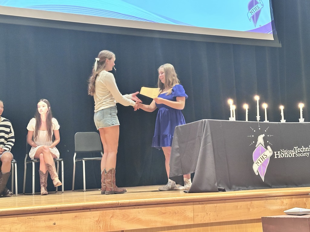 An officer welcomes an inductee during  a National Technical Honor Society induction ceremony.