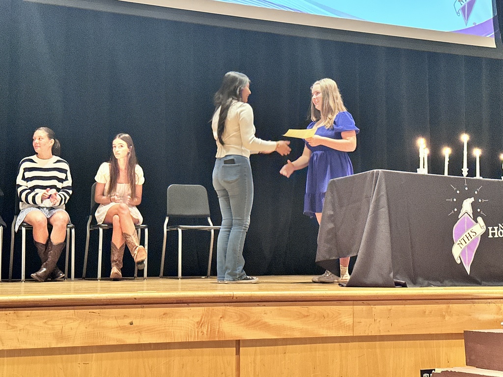 An officer welcomes an inductee during  a National Technical Honor Society induction ceremony.