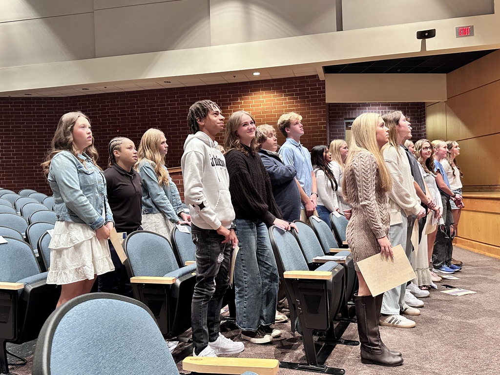 A group of students take a pledge at a National Technical Honor Society induction ceremony.