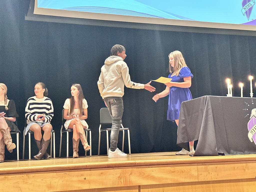 An officer welcomes an inductee during  a National Technical Honor Society induction ceremony.
