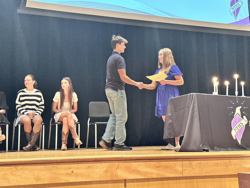 An officer welcomes an inductee during  a National Technical Honor Society induction ceremony.