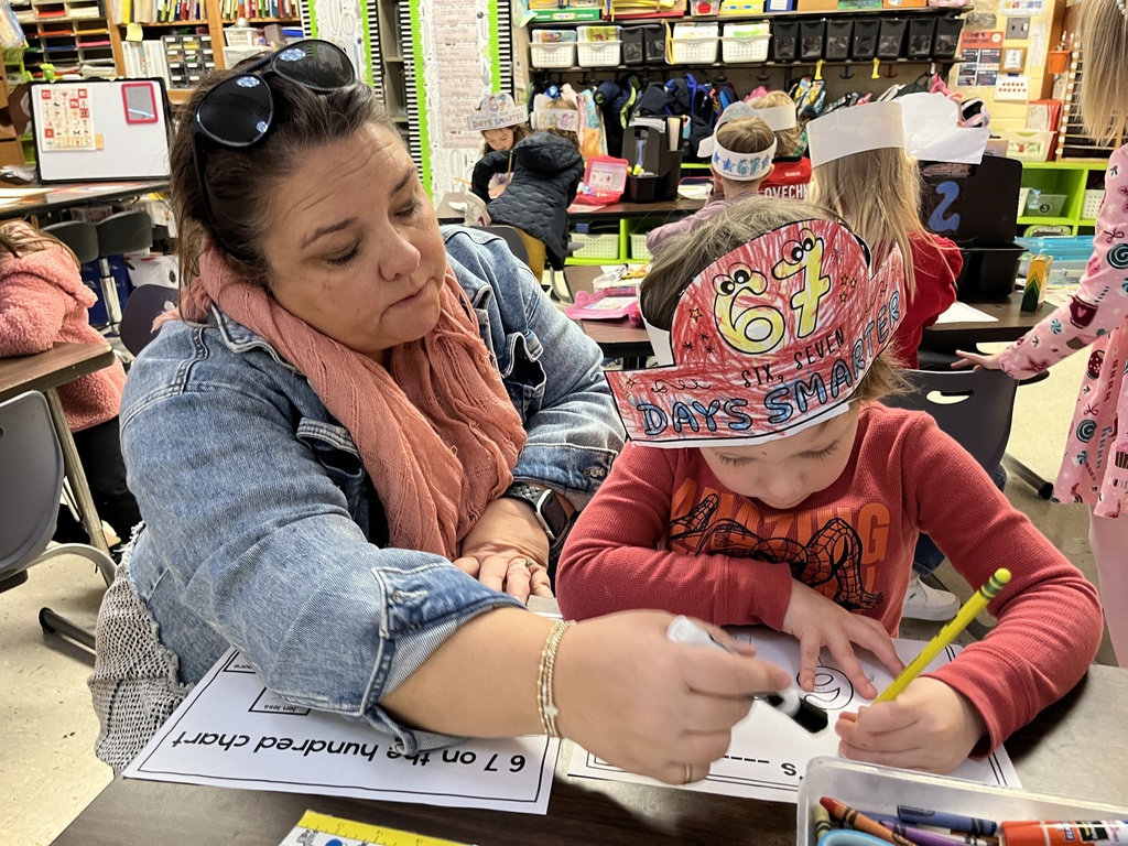 A teacher helps a student in class work on a 67th day of school activity. 