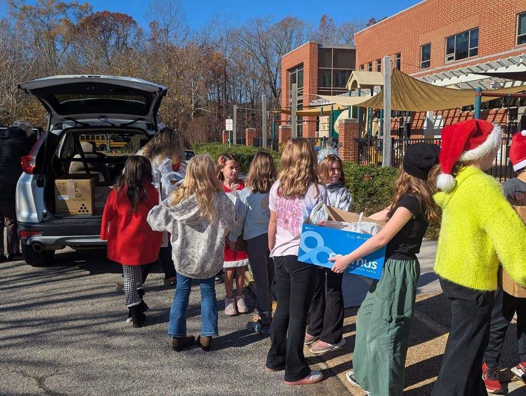 A line of students load donation drive items into a car.