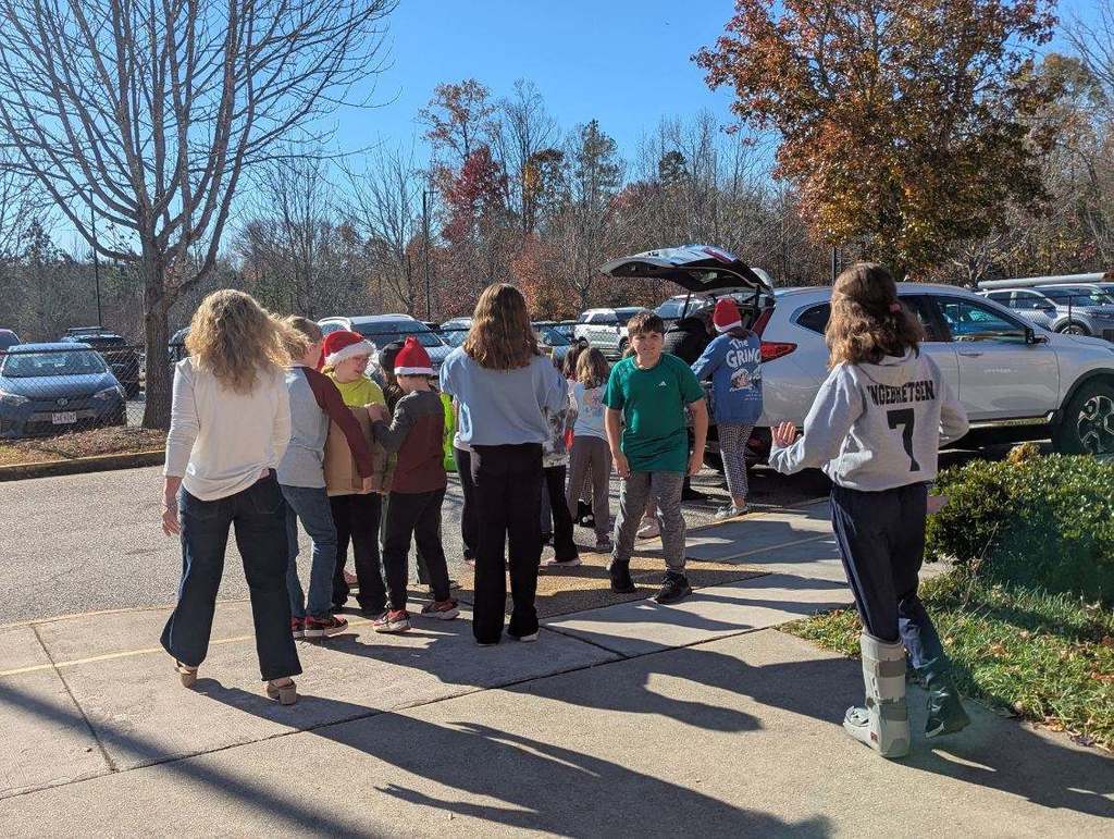 A line of students load donation drive items into a car.