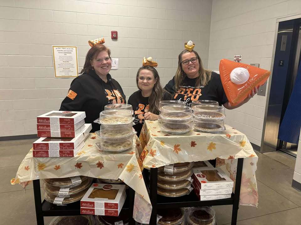 Three adults pose with carts full of pie that will be given away to staff members.