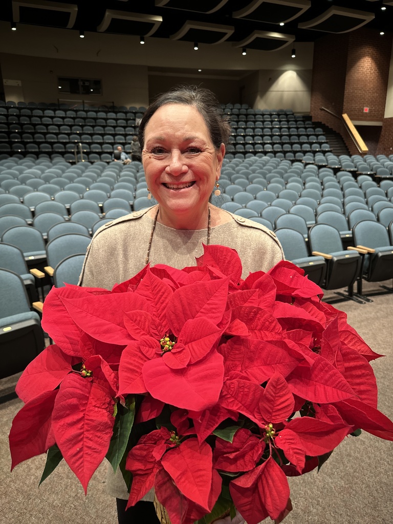 A woman poses for a photo holding poinsettias. 