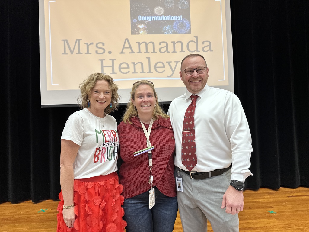 Two women and one man pose for a photo. A slide behind them reads COngratulations Mrs. Amanda Henley.