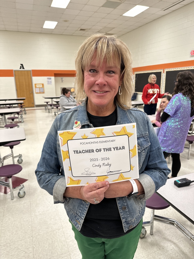 A woman poses for a photo with a Teacher of the Year certificate. 