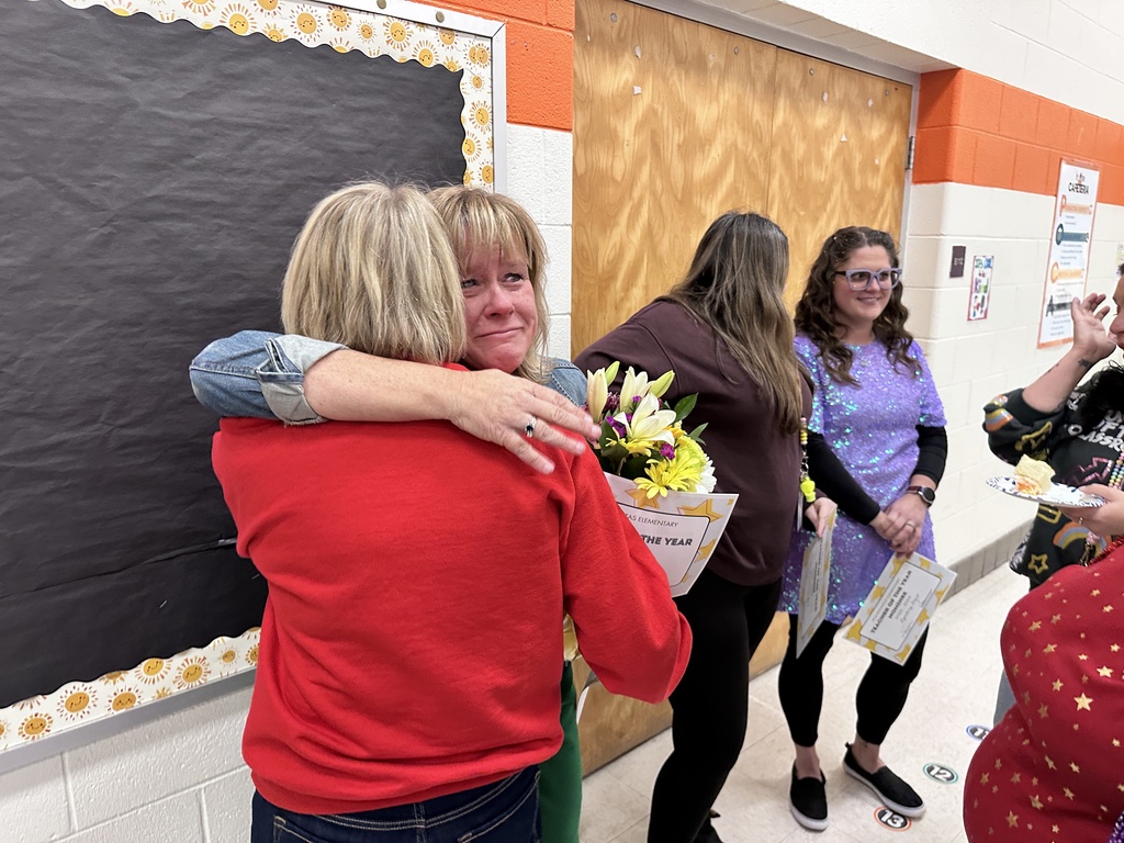 An overwhelmed woman in hugged by another woman.