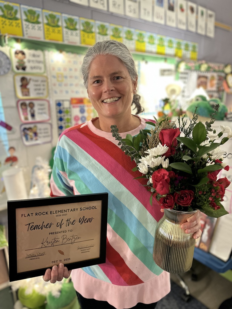 A woman poses for a photo holding  a certificate and flowers. 