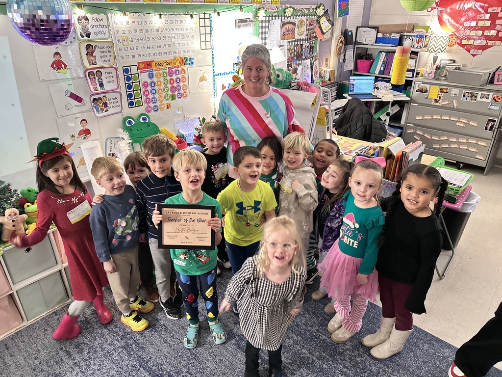 A woman poses for a photo with a group of students. 
