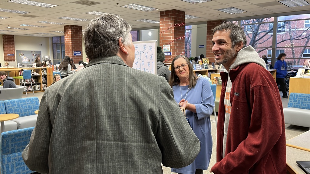 A woman presents an National Board Certified Teacher name plaque to an educator.