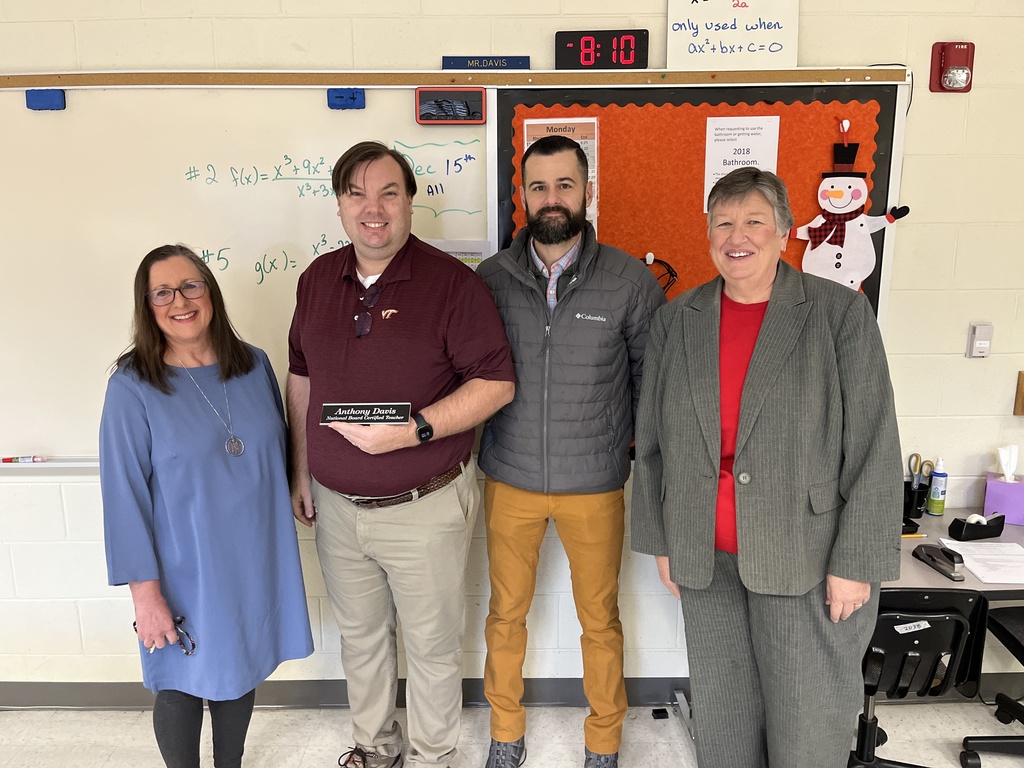 A man who has achieved National Board Certified Teacher poses with another man and two women.