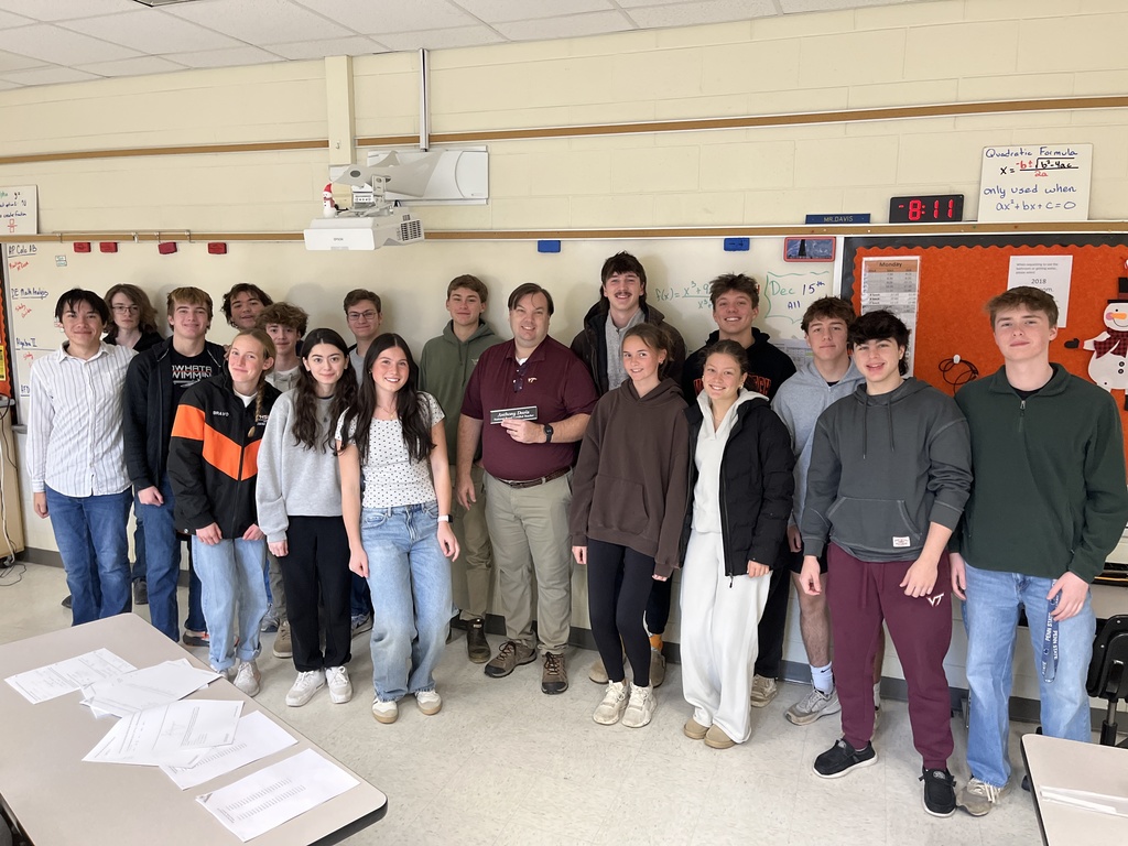 A man who has achieved National Board Certified Teacher poses with students.