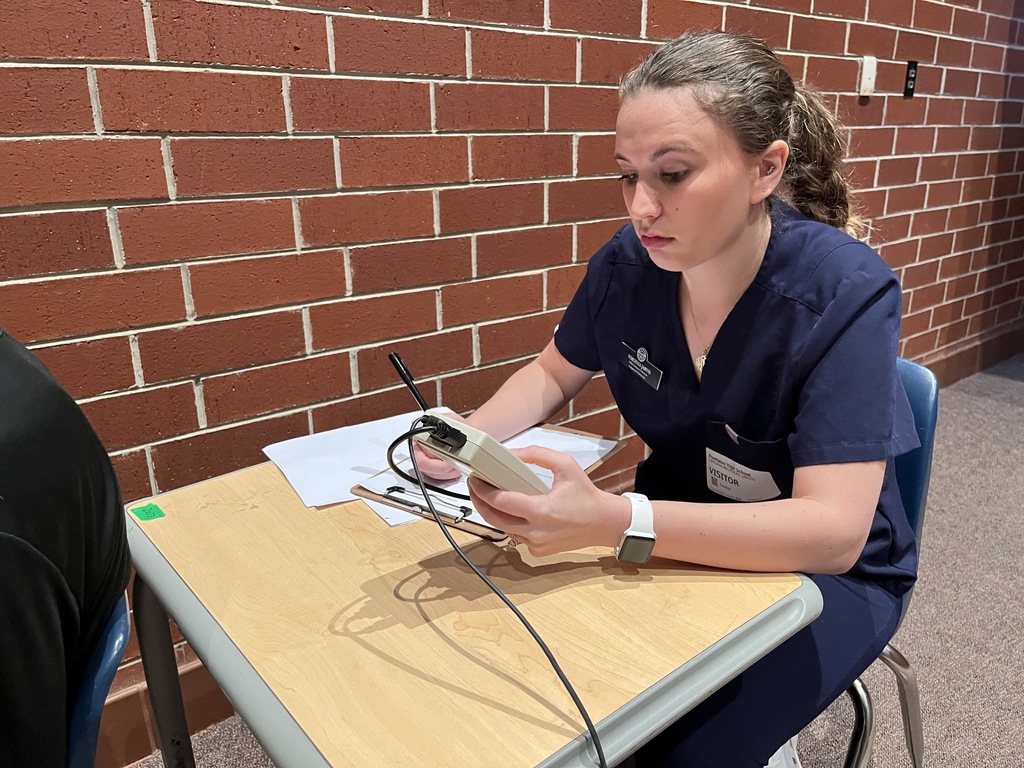 A college student conducts a hearing test at a high school.