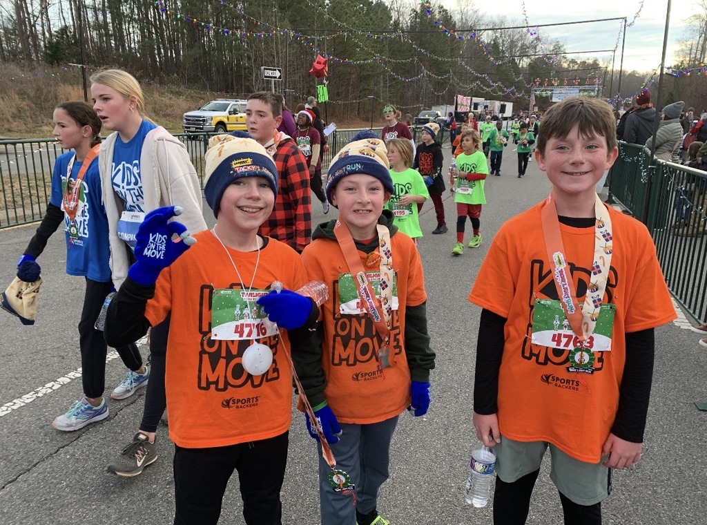 Students  wearing Kids on the Move shirts pose for a photo after a race.