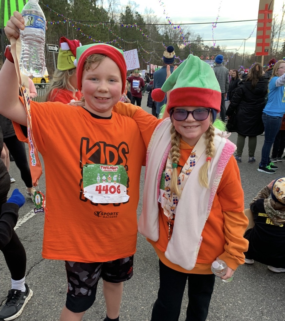 Students  wearing Kids on the Move shirts pose for a photo after a race.
