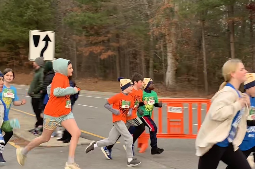 Students  wearing Kids on the Move shirts run in a race.
