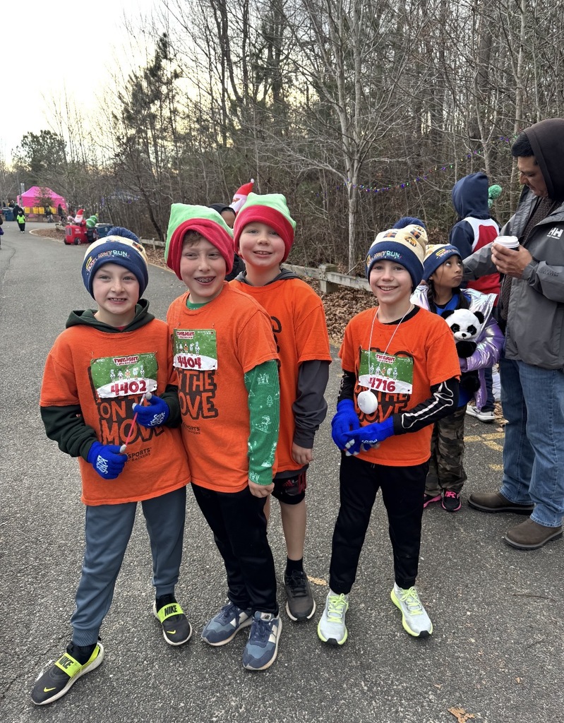 Students  wearing Kids on the Move shirts pose for a photo after a race.