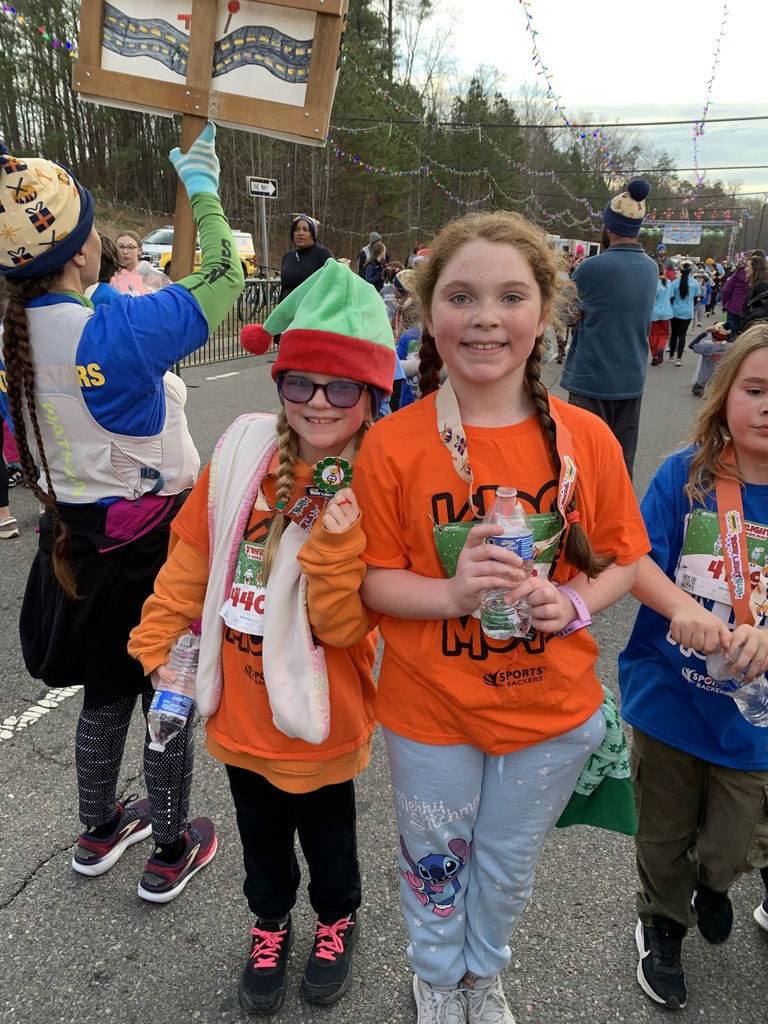Students  wearing Kids on the Move shirts pose for a photo after a race.