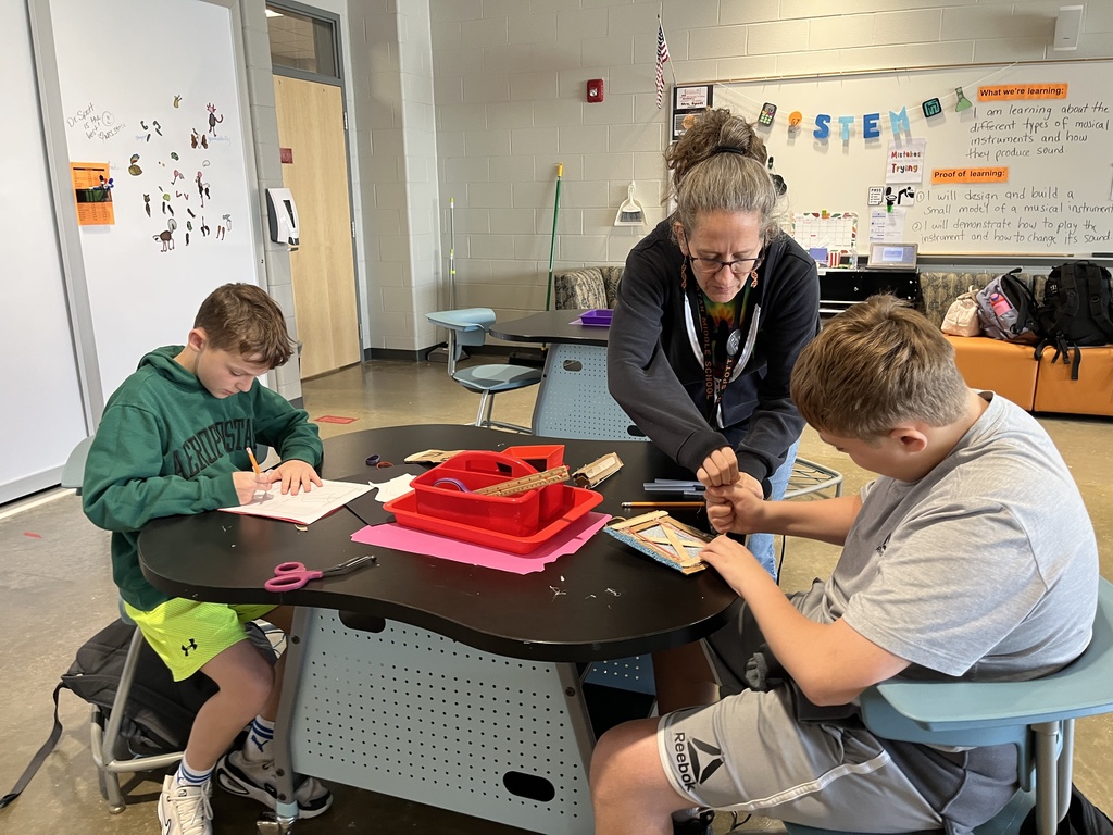 Students engineer models of musical instruments in the innovation lab. A teacher helps.