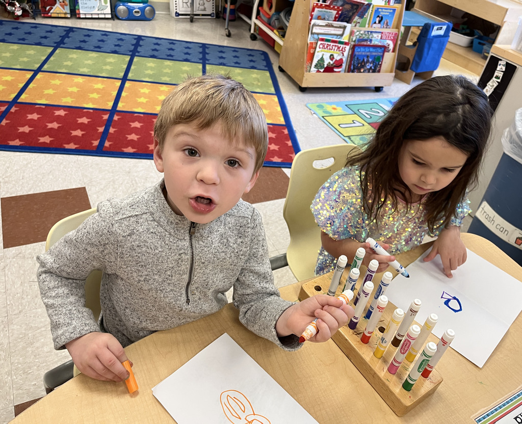 Preschoolers make a card for their student teacher.