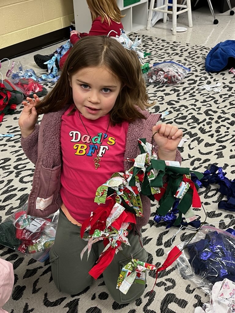 A child makes a fabric wreath in class. 