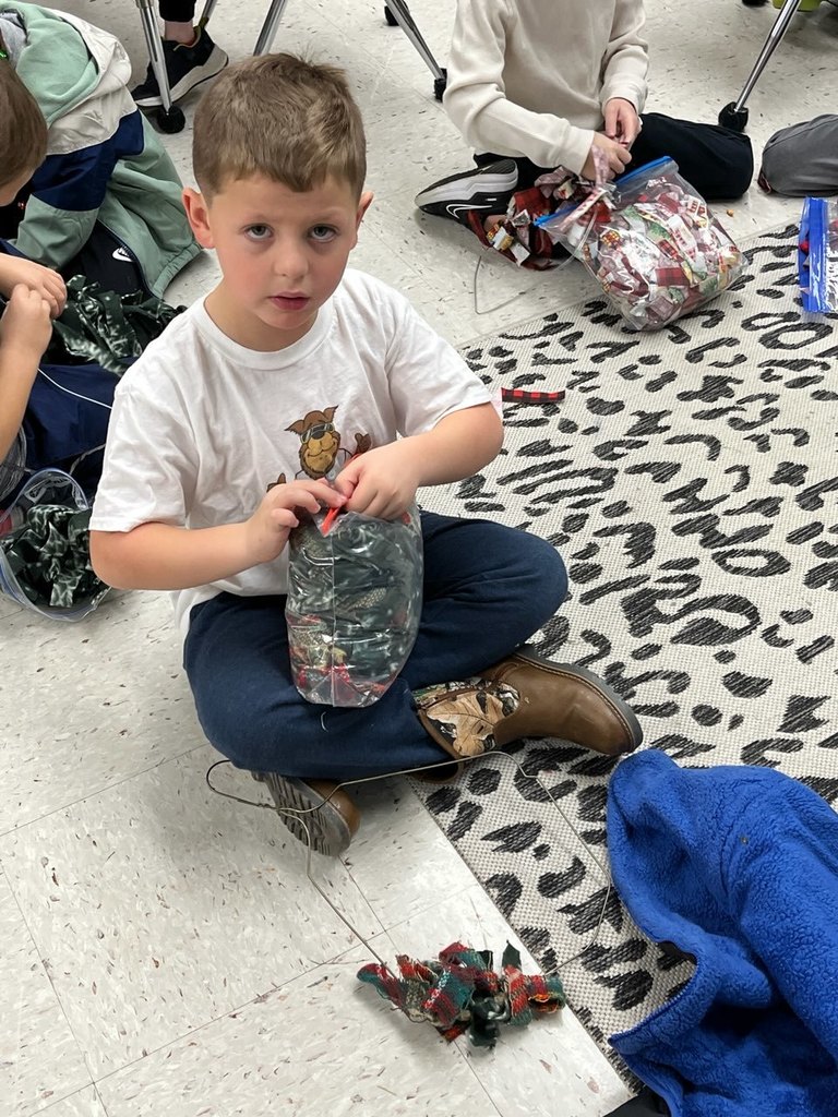 A child makes a fabric wreath in class. 
