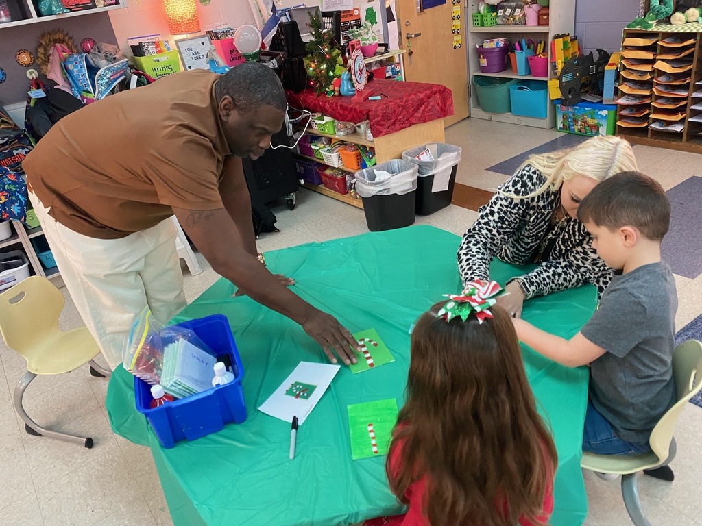 Adults help students work on craft projects.