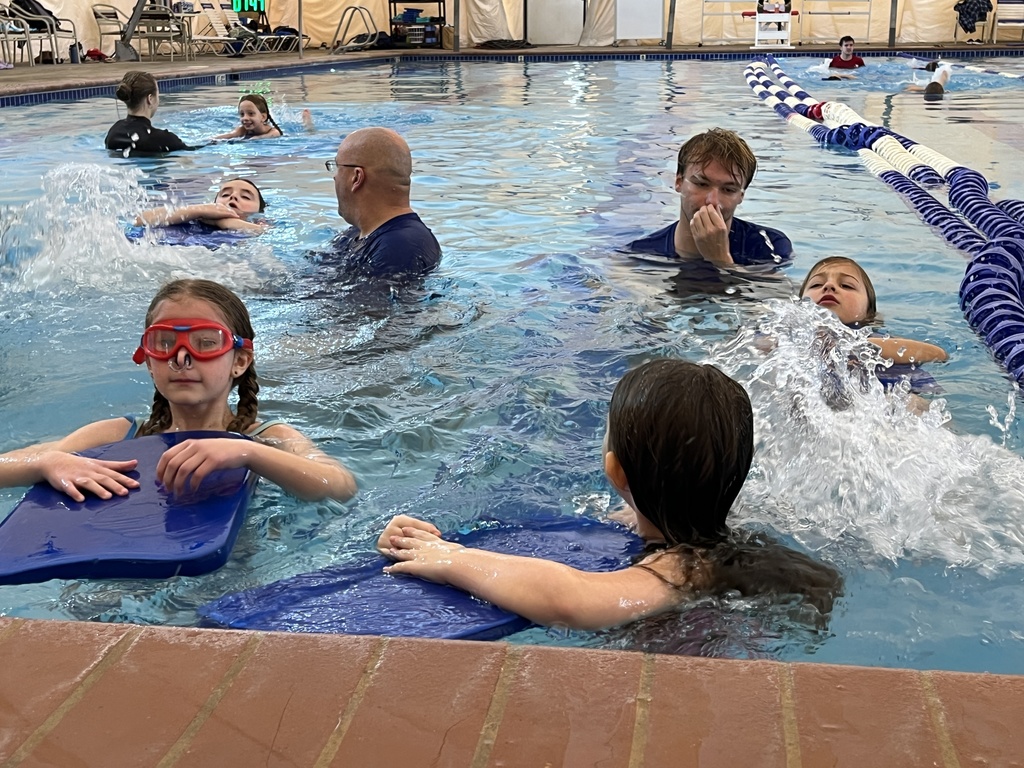 Instructors help children learn to swim.