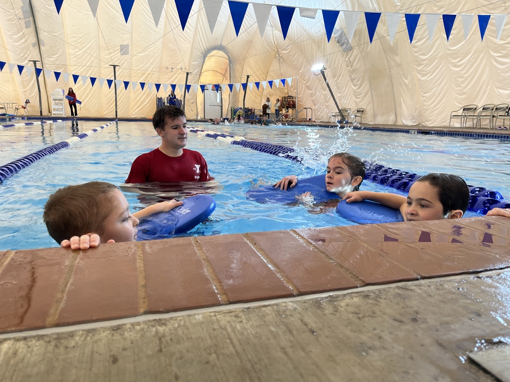 An instructor helps children learn to swim.