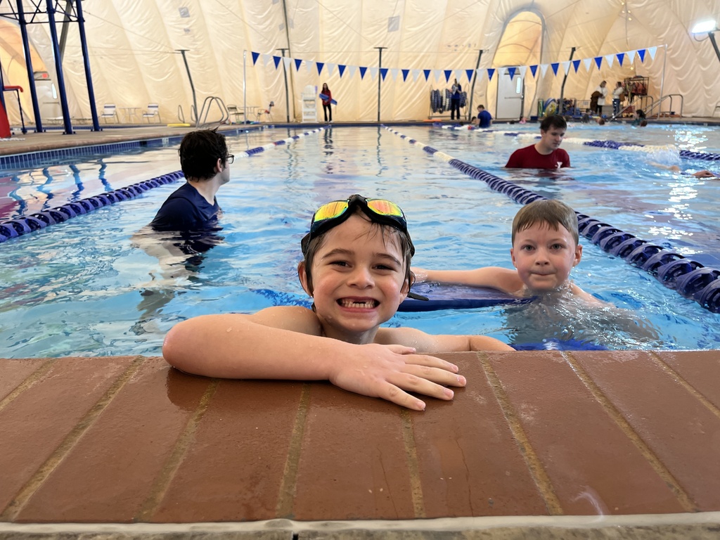 An instructor helps children learn to swim.