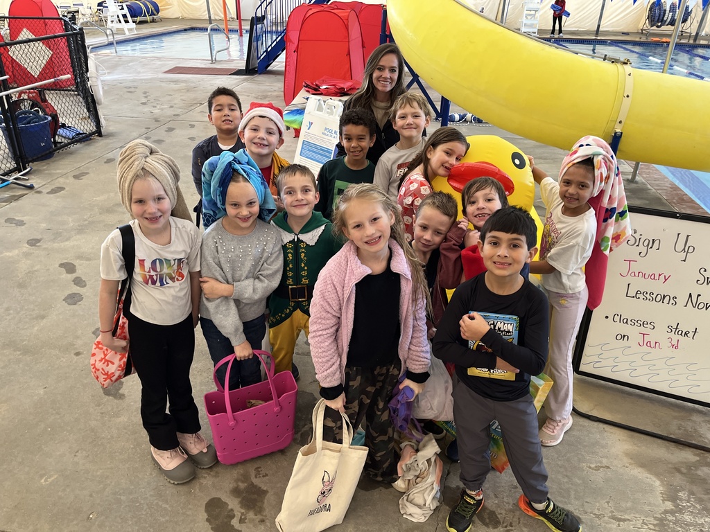 A class and their teacher pose for a photo by a pool.